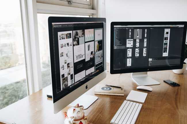 Silver and Black iMacs on Top of Brown Wooden Table